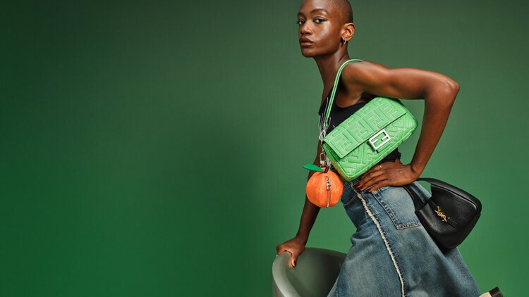 Model wearing several designer handbags.