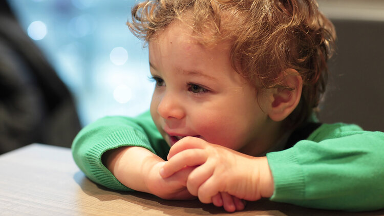 Toddler smiling in a green sweater.
