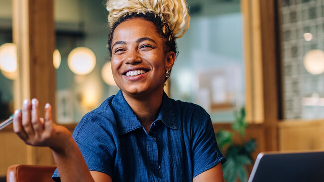 Employee smiling during a conversation in a collaborative workspace.