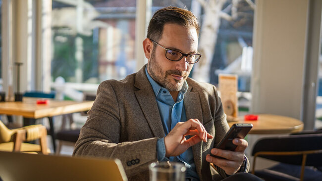 Employee using a smartphone while working in a café setting.